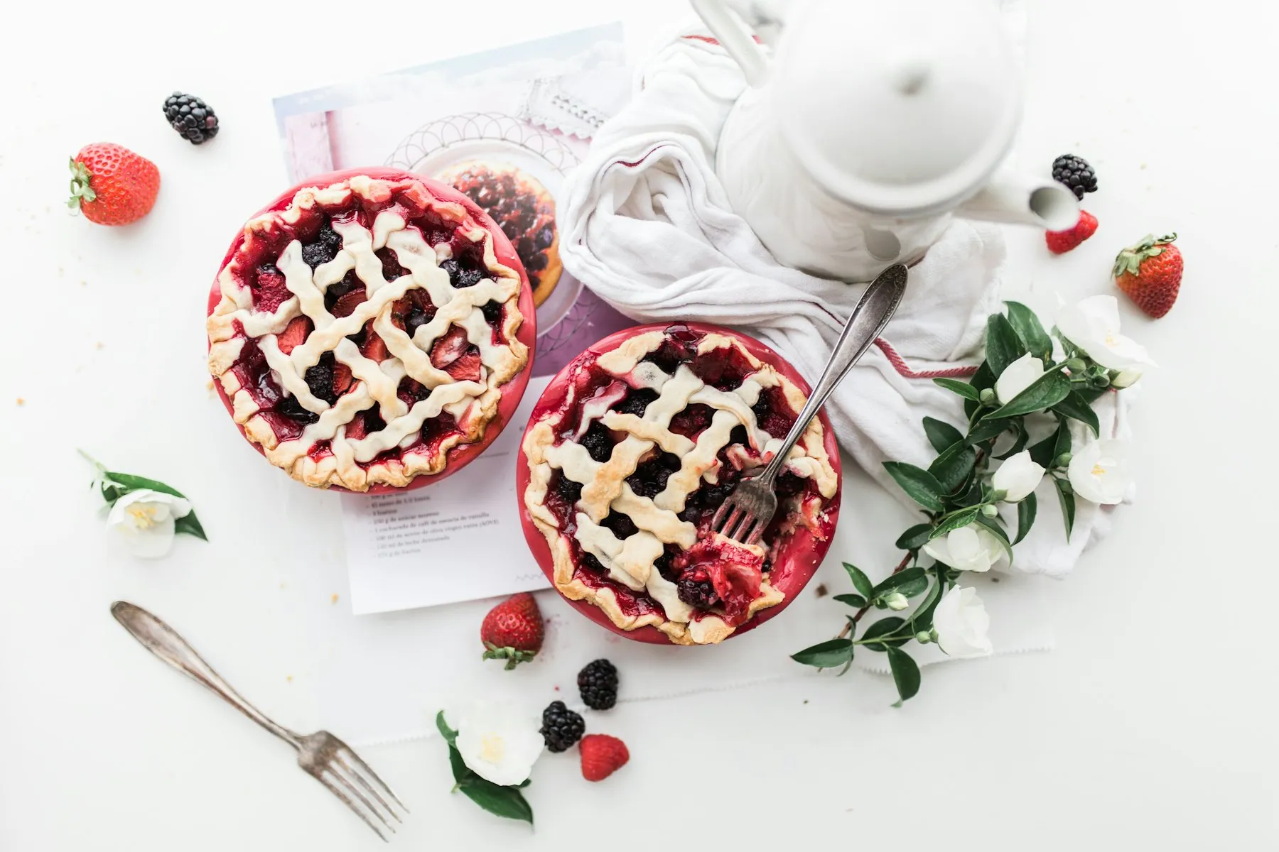 Two mixed-berry lattice pies with a vintage teapot