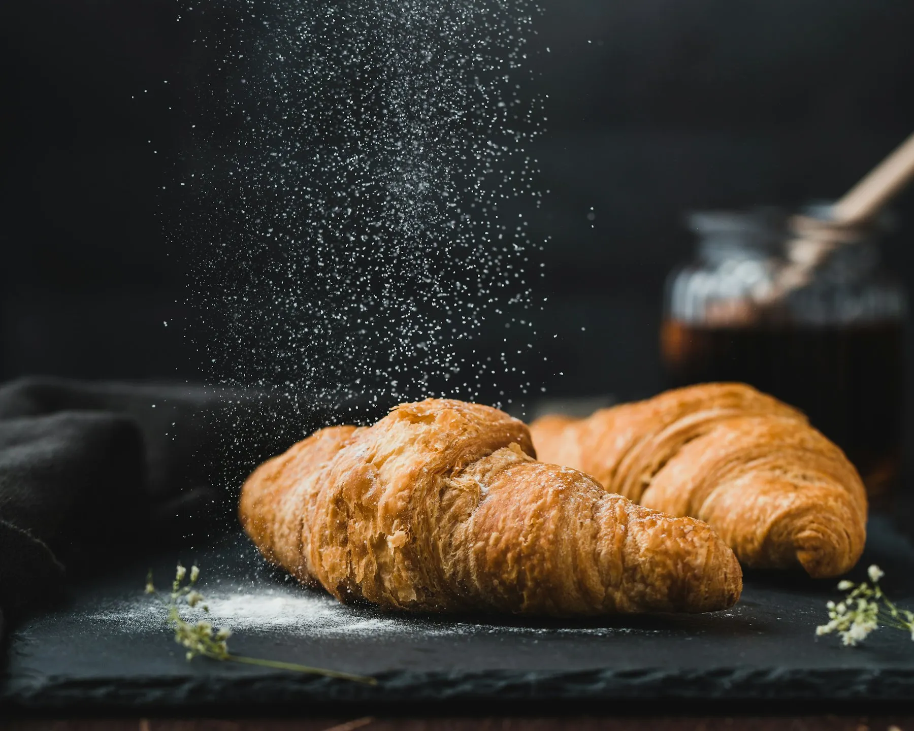 Golden flaky croissants dusted with icing sugar