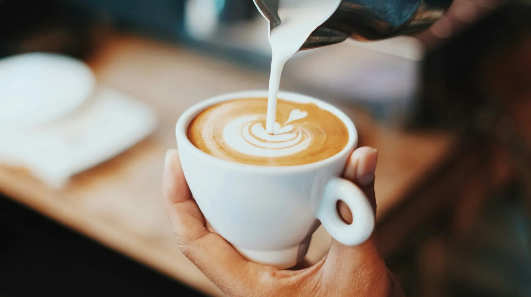 Barista pouring latte art into a flat white